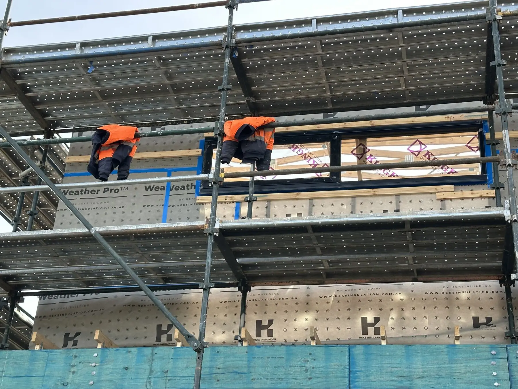 Installers on scaffolding fitting HEKS wall wrap on a townhouse